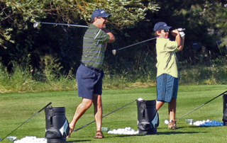 Father & son teeing off at golf range.