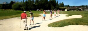 Lady golfers teeing from a sandtrap.
