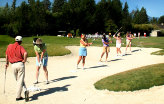 Lady golfers teeing from a sandtrap.