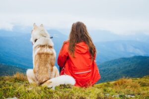 Woman sitting with dog on a hill.
