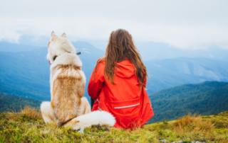 Woman sitting with dog on a hill.