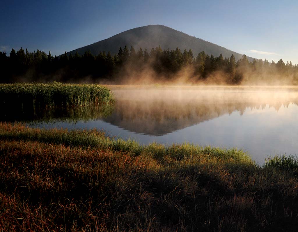 Mountain reflected in lake with morning fog.