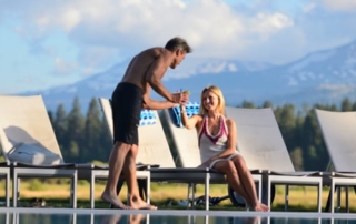 Man bringing a woman a drink poolside.