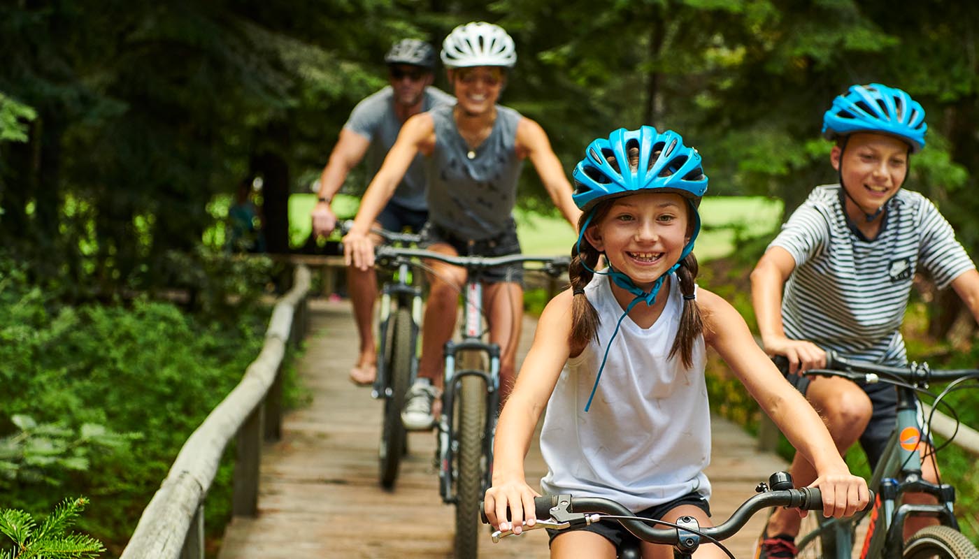 Family biking on a wooden bridge.