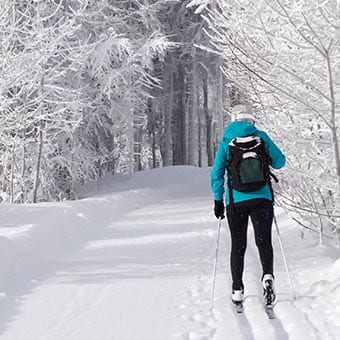 Person cross country skiing down a winter trail.