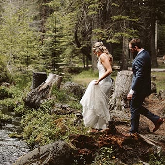 Wedding couple walking near a stream.