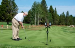 A picture of a man putting at a golf course.