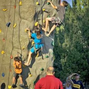 Kids climbing a rock wall during their Oregon summer vacation.