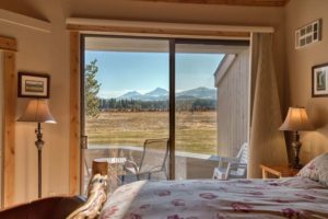 A bedroom of a Sisters cabin rental with mountain views to relax in after visiting a nearby Oregon fish hatchery.